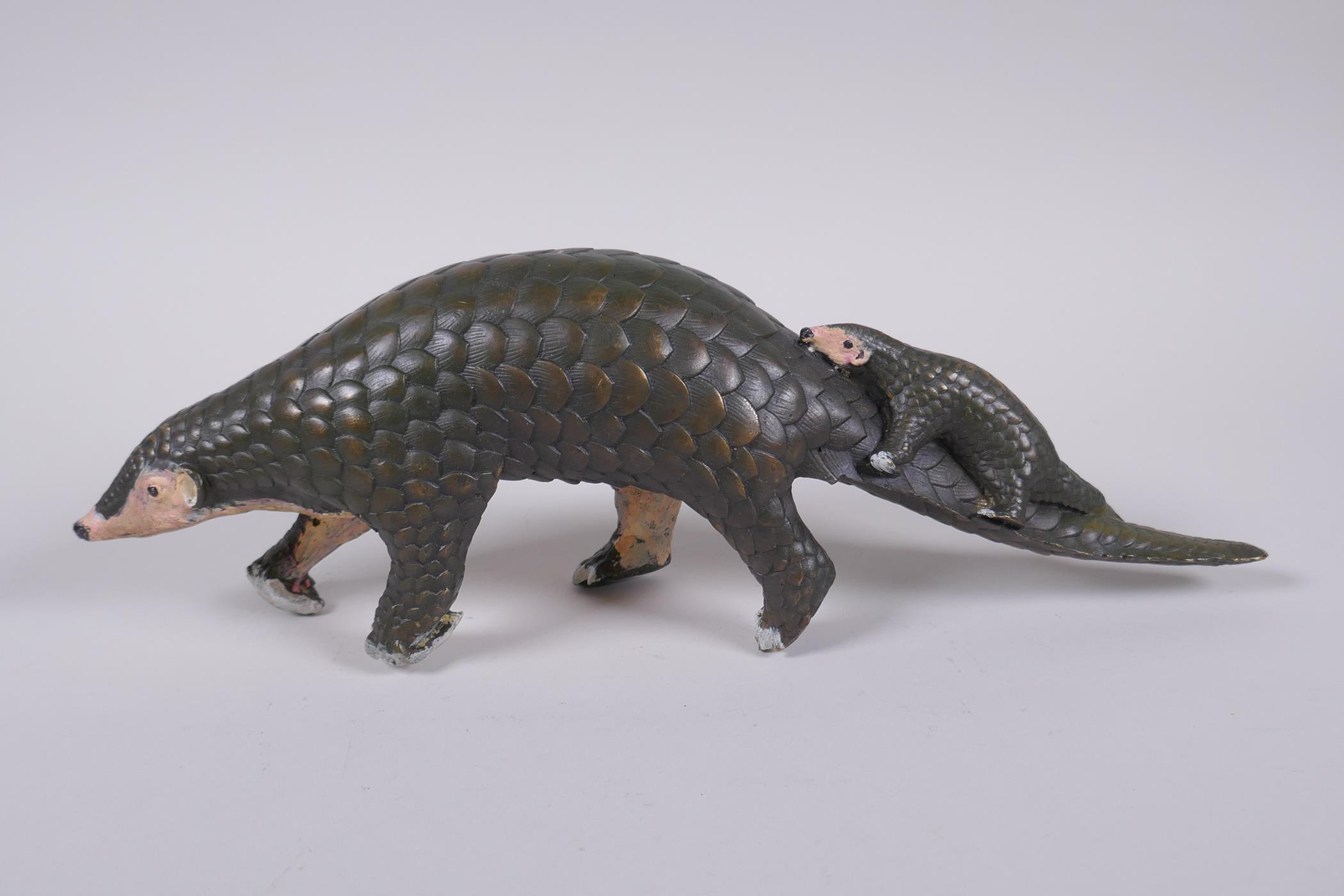 A cold painted filled bronze figure of a pangolin with a pup riding on its back, 32cm long