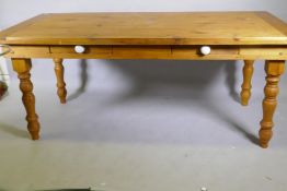 A pine farmhouse style table with two drawers, raised on turned supports, 90 x 180 x 76cm, legs