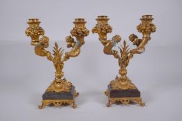 A pair of ormolu two branch candlesticks, decorated with fish tailed putti, 27cm high