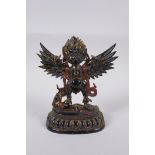 A Tibetan lacquered and gilt bronze of Garuda standing on the back of a figure, 17cm high