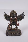 A Tibetan lacquered and gilt bronze of Garuda standing on the back of a figure, 17cm high