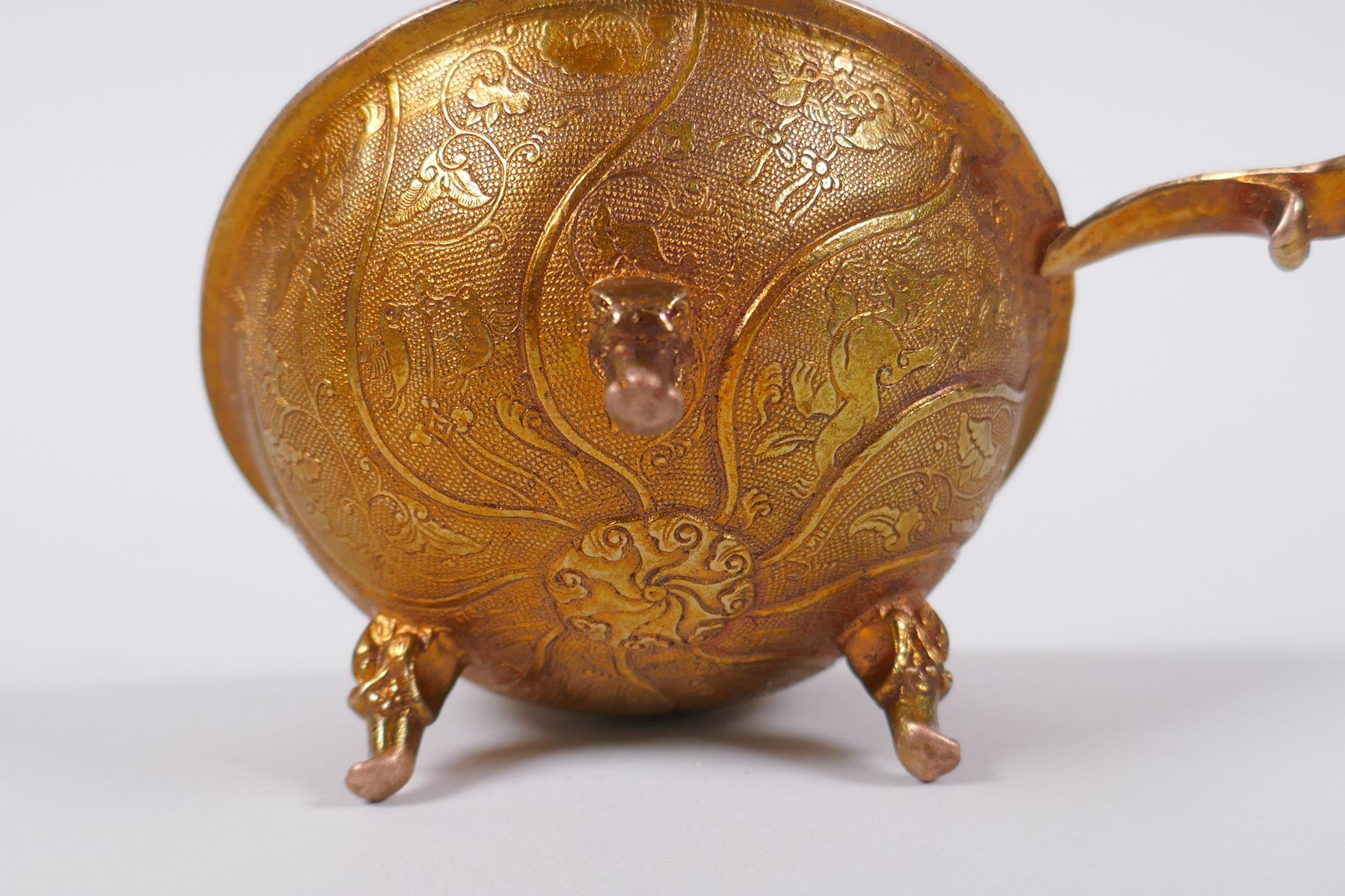 A Chinese gilt metal libation cup on tripod supports with kylin decoration, 9cm diameter - Image 3 of 3