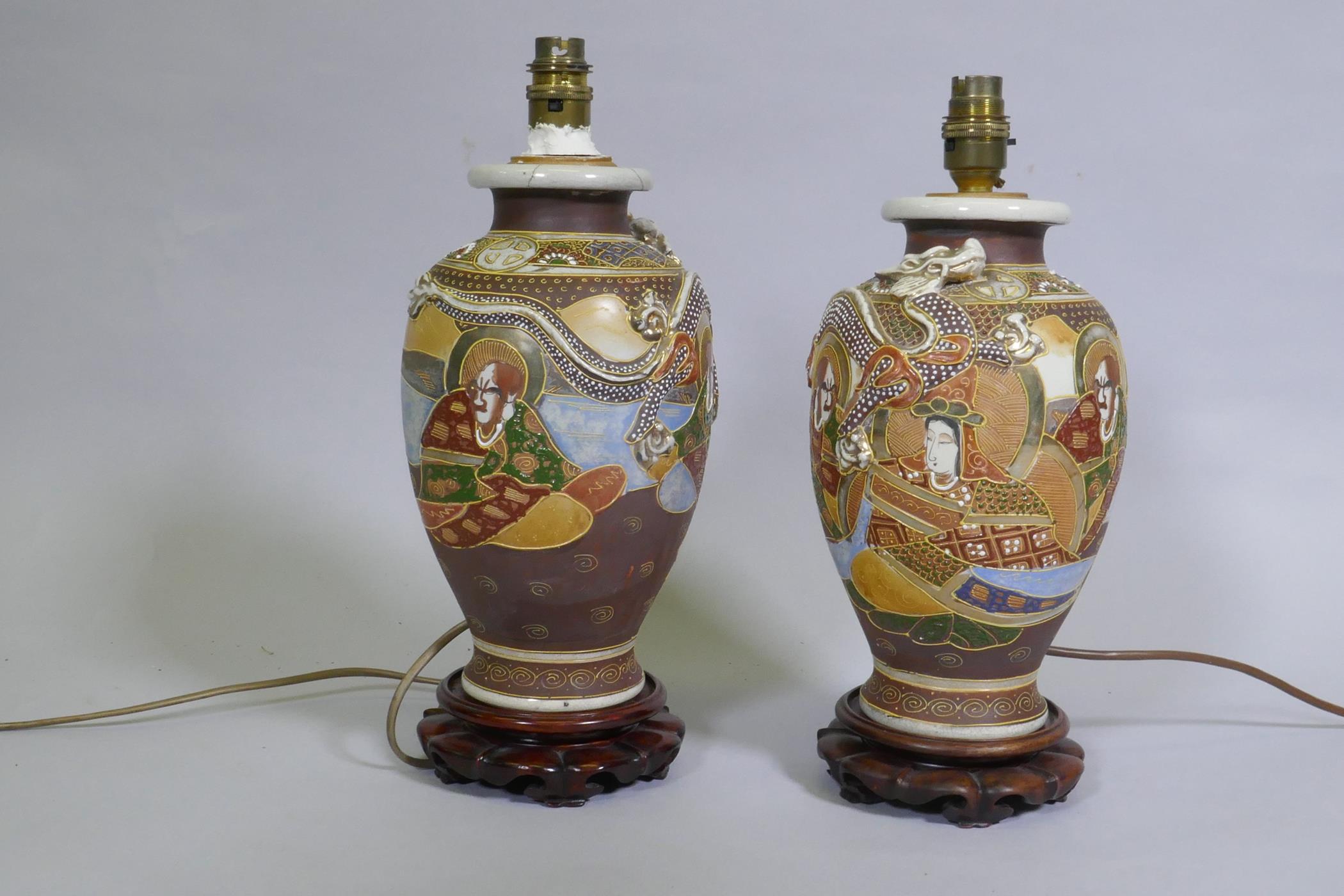 A pair of oriental ceramic table lamps mounted on carved wood bases, 34cm high