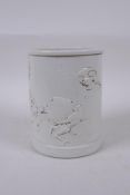 A Chinese cream ground porcelain brush pot with raised decoration of a monkey carrying a peach,