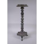 A Persian bronze oil lamp stand, raised on tripod support with engraved script decoration to the