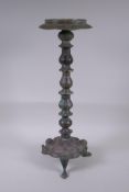 A Persian bronze oil lamp stand, raised on tripod support with engraved script decoration to the