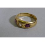 A yellow metal gypsy ring, set with a diamond flanked by two rubies, hallmark 'P' date letter,