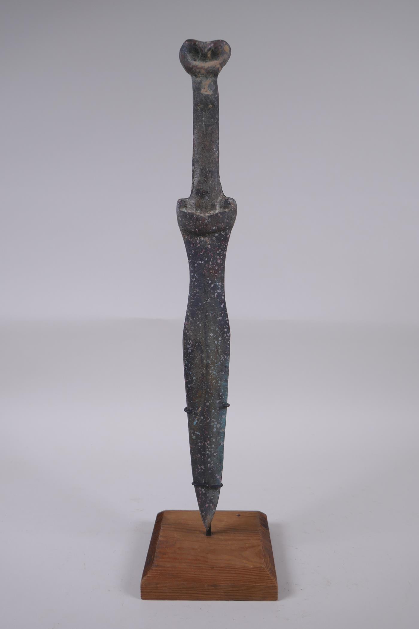 A Chinese archaic style bronze dagger on a display stand, 40cm high