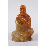 A Chinese faux amber soapstone figure/seal in the form of Lo-han, 12cm high