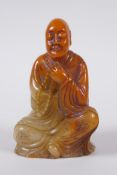 A Chinese faux amber soapstone figure/seal in the form of Lo-han, 12cm high