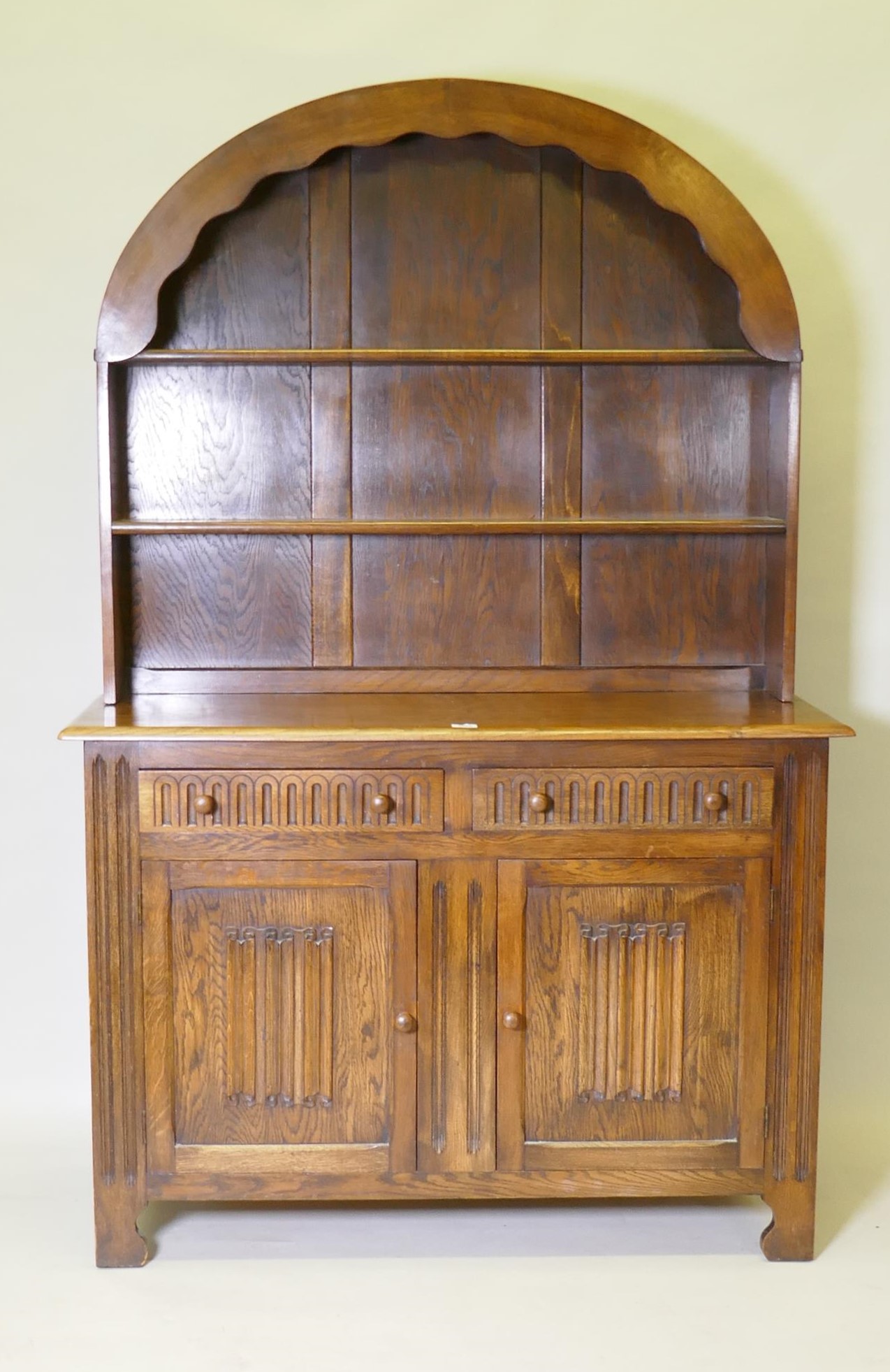 A mid century oak dresser with dome shaped upper rack on a base of two drawers over two cupboards,