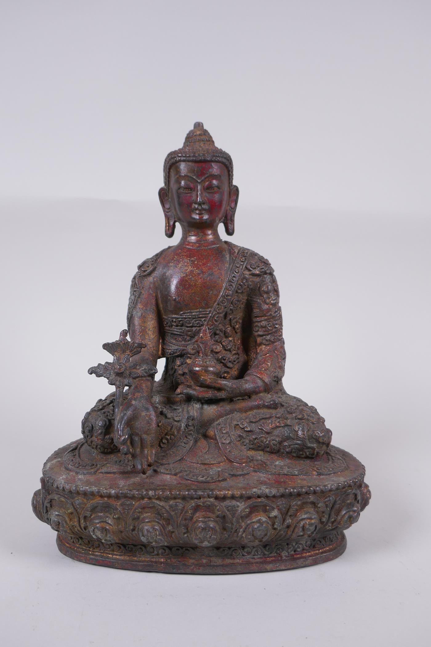 A Tibetan bronzed metal Buddha with the remnants of gilt and copper patina, impressed double vajra