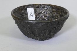 An oriental bronze bowl with raised dragon decoration, 15cm diameter