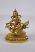 A Sino Tibetan gilt bronze figure of Buddha seated on the back of a phoenix, with inset coral,