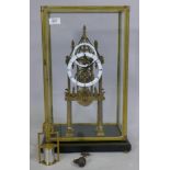 A skeleton clock with open movement and two concentric enamel dials raised on a four column base and