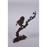 A Japanese style bronze okimono of a bird perched on a branch, 10cm high