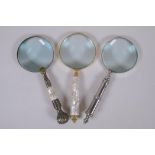 Two brass magnifying glasses with mother of pearl handles, and a similar chromed metal magnifying