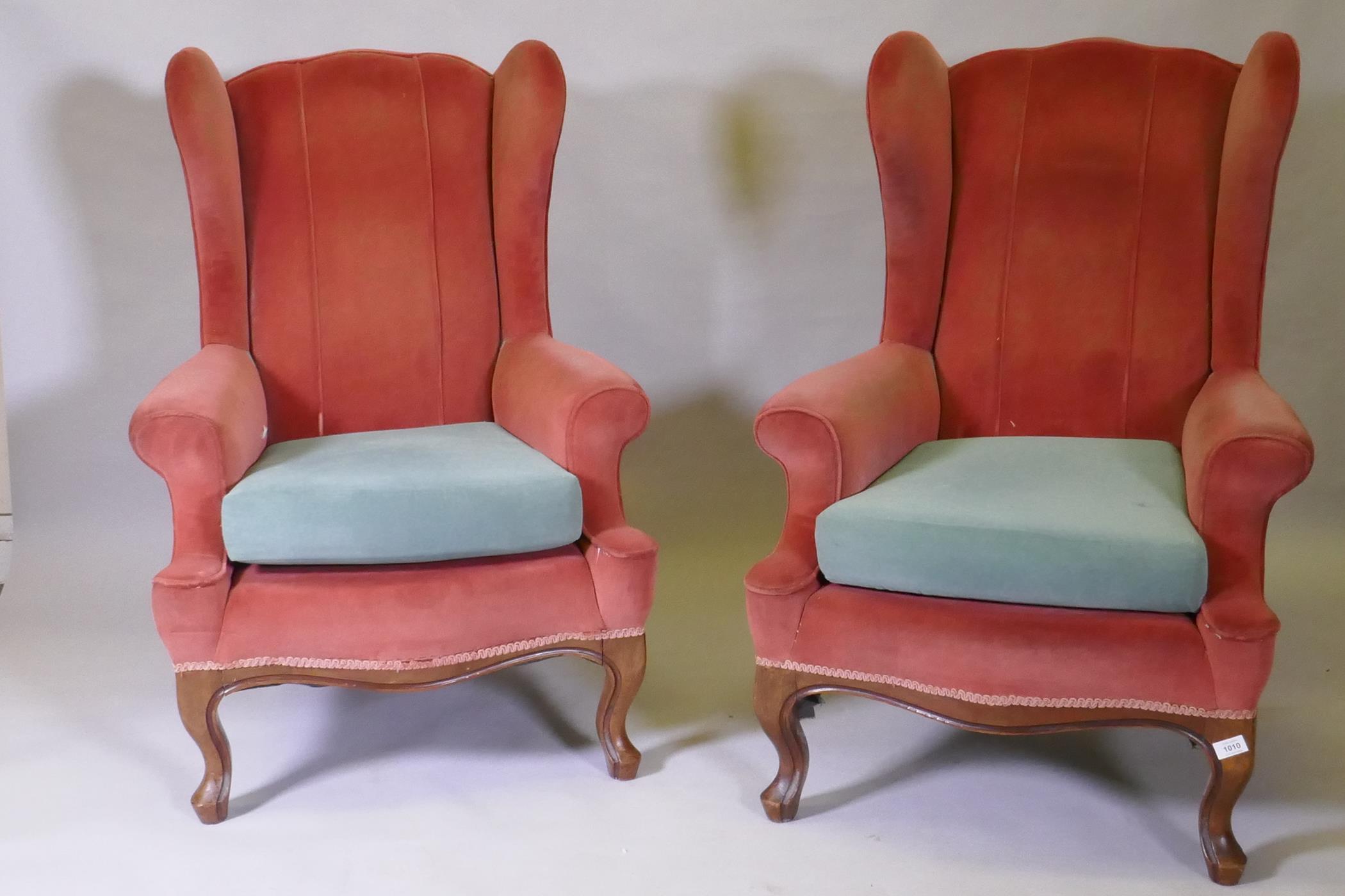 A pair of Georgian style wing back armchairs, with shaped backs