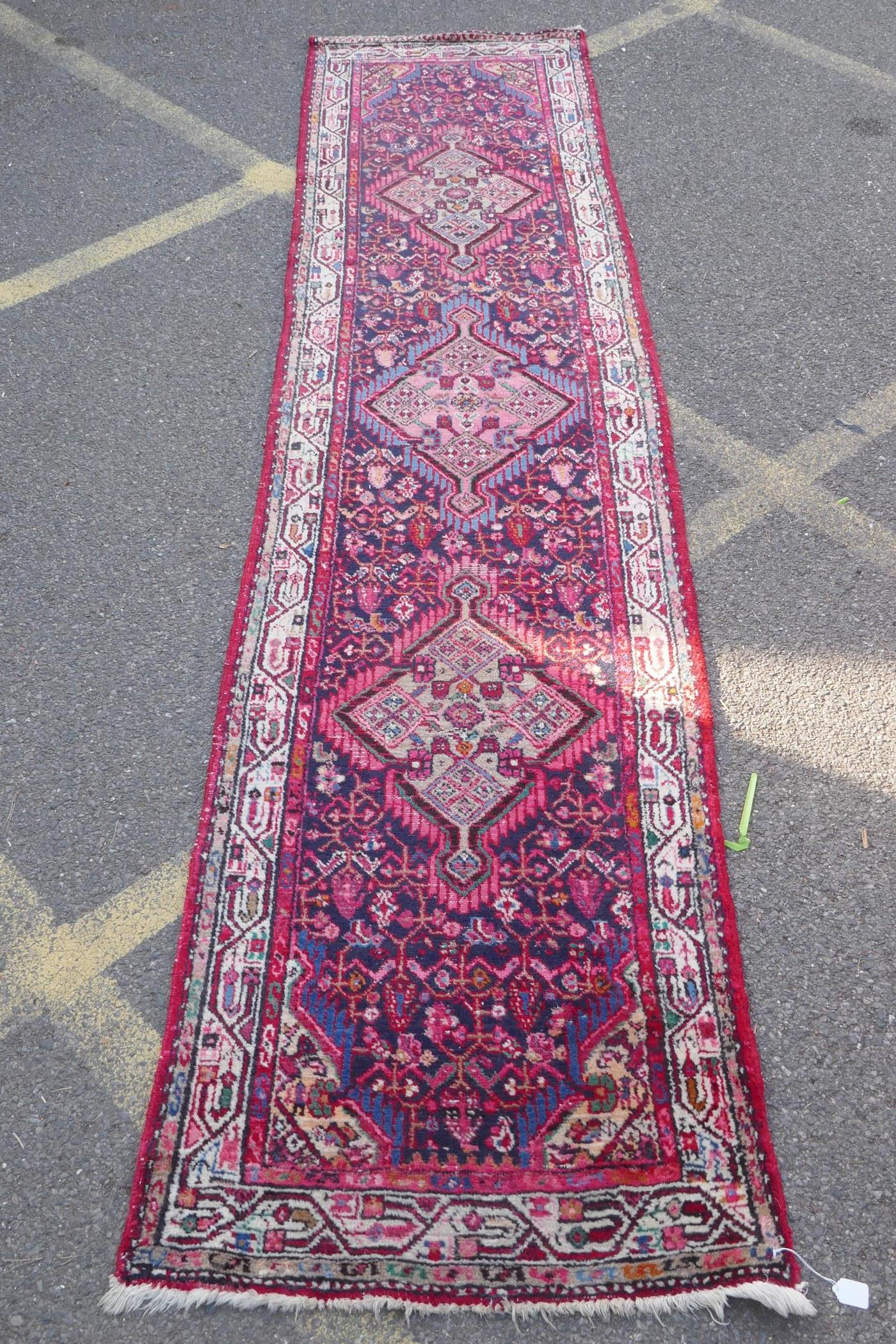 A Persian red ground wool runner with multi colour geometric medallion design, 85 x 340cm