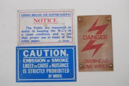 Three vintage rail signs, Danger: Overhead Live Wires, Caution: Emissions of Smoke, and a W.C.