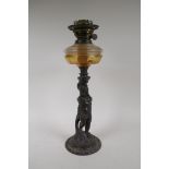 An early C20th oil lamp with cast iron base in the form of a putto, 47cm high