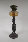 An early C20th oil lamp with cast iron base in the form of a putto, 47cm high