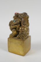 A Chinese filled gilt bronze seal, the knop in the form of kylin inset with coral and turquoise