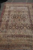 An antique Persian carpet with stylised flora and fauna designs on a faded gold field, with red