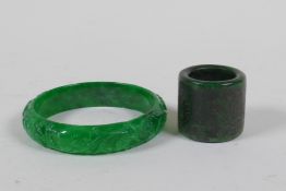 A Chinese carved apple green jade bangle, and a green hardstone archers ring, bangle 7cm diameter