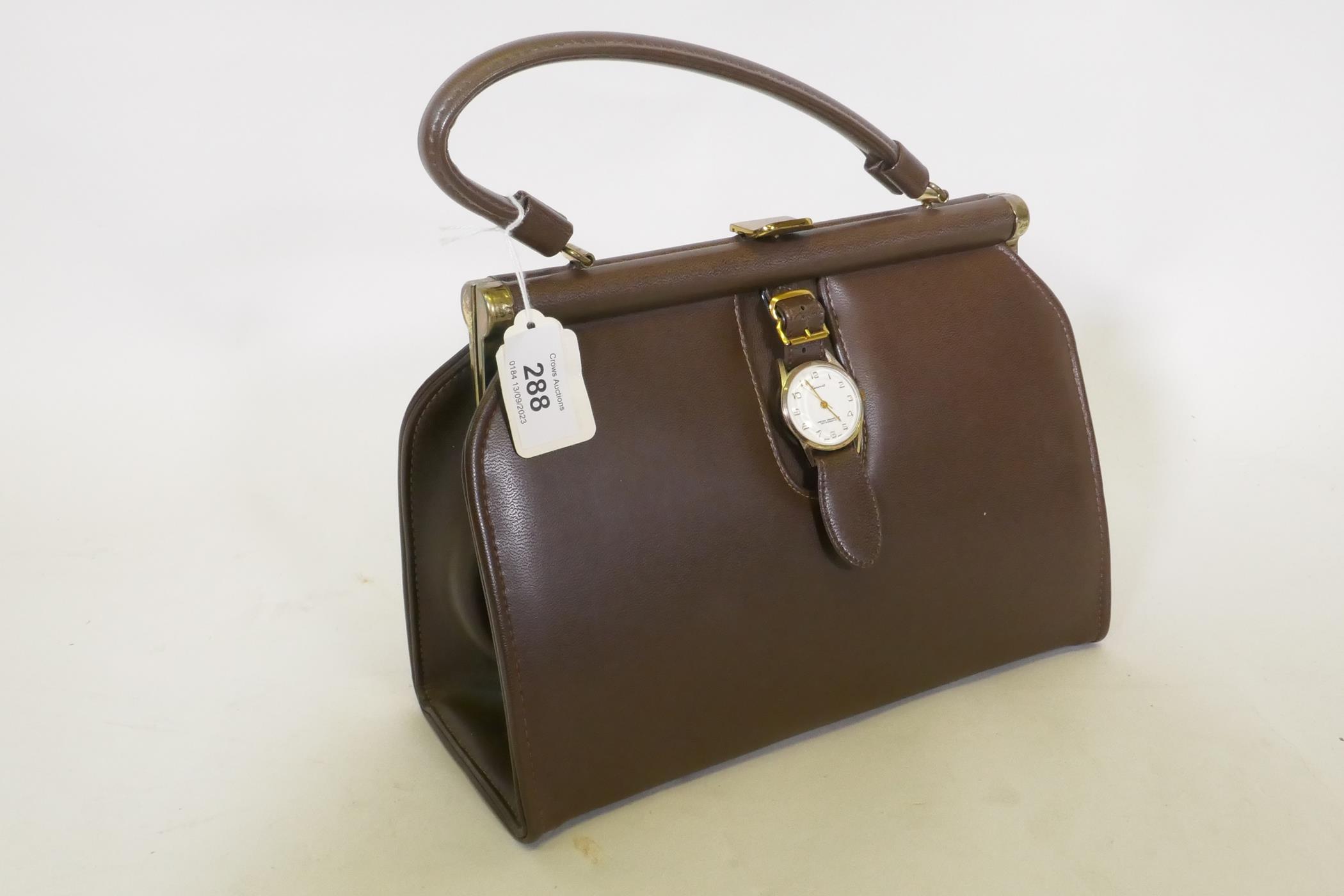 A vintage leather handbag with Genovit watch clasp and brass mounts, 27 x 20cm