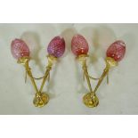 A pair of ormolu two branch wall sconces of trumpet form with cranberry glass shades, 56cm high