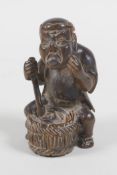 A Japanese carved wood netsuke in the form of a man making mochi, 5cm high