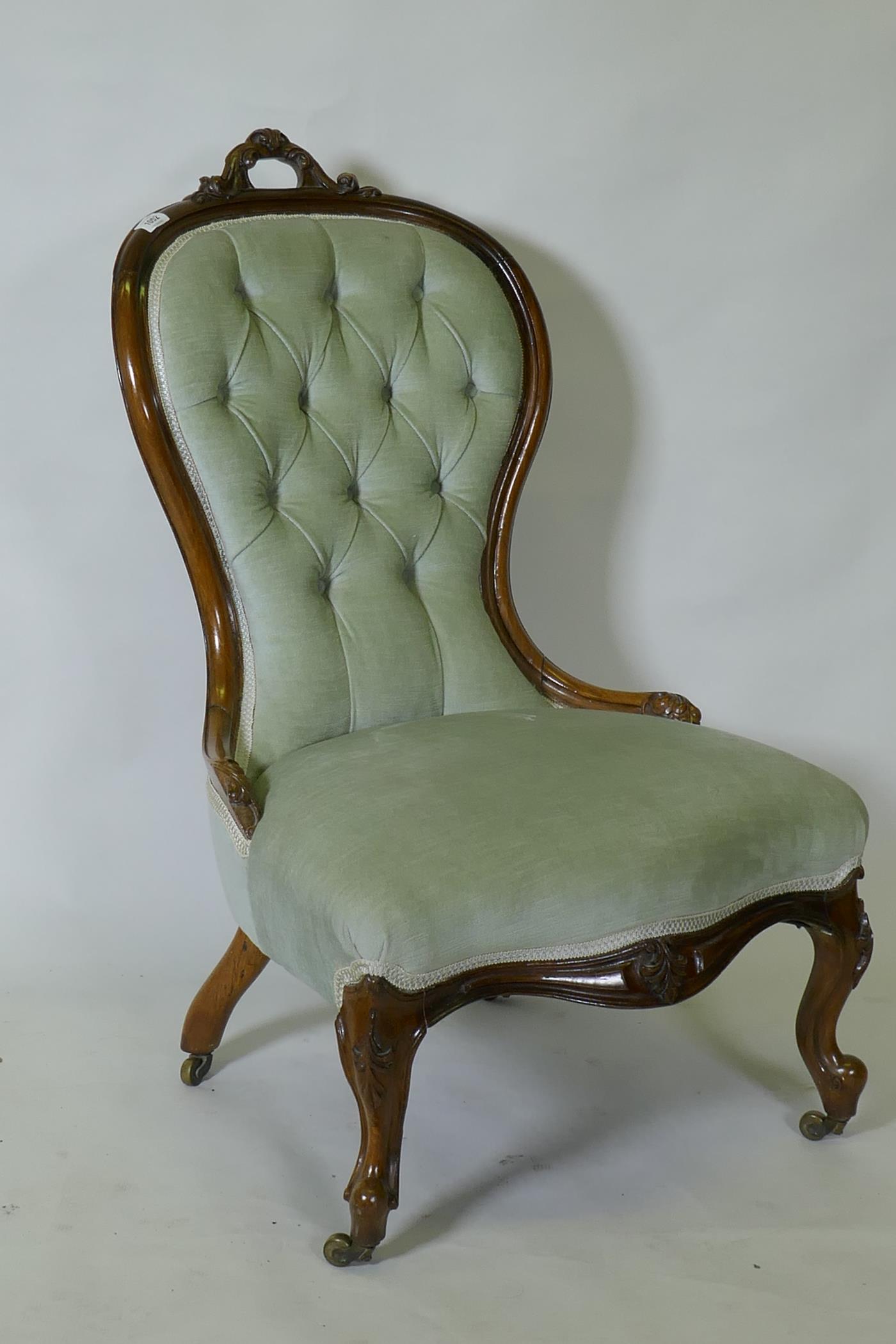 A Victorian carved walnut nursing chair, raised on cabriole supports with brass castors - Image 2 of 2