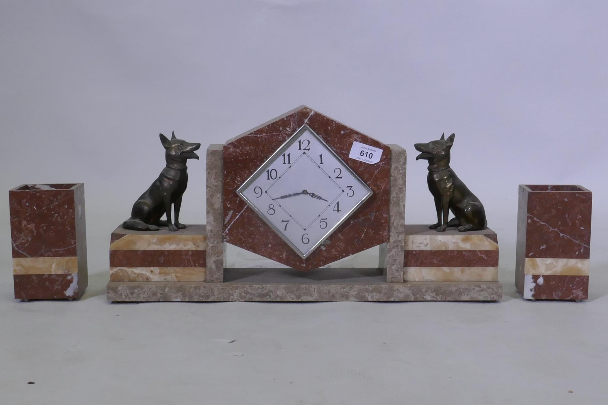 An Art Deco French rouge marble mantel clock garniture, with bronzed metal figures of Alsatian dogs,