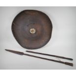 A C19th Ethiopian tribal hide shield and two ceremonial hardwood spears, one AF, shield 57cm