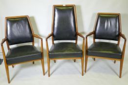 A set of three mid century teak boardroom elbow chairs with leather upholstered seats and backs