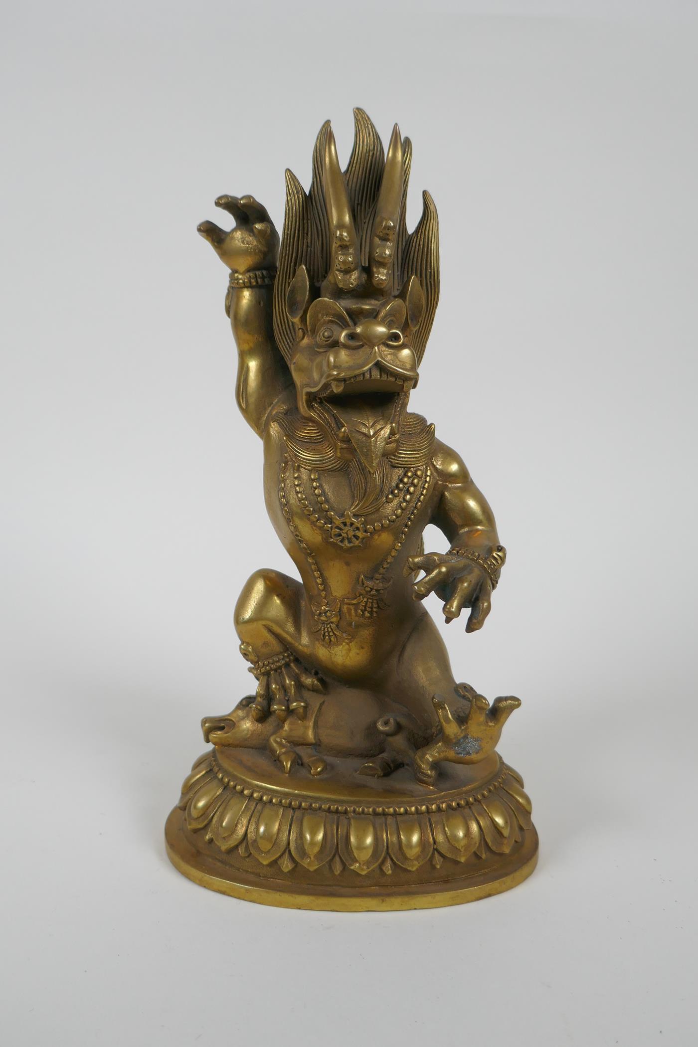 A Tibetan bronze of a wrathful beast seated on a pig, double vajra mark to base, 22cm high