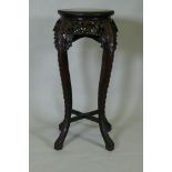 A tall Chinese hardwood jardiniere stand with shaped top inset with marble, with carved and
