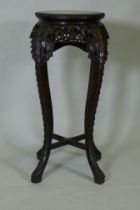 A tall Chinese hardwood jardiniere stand with shaped top inset with marble, with carved and