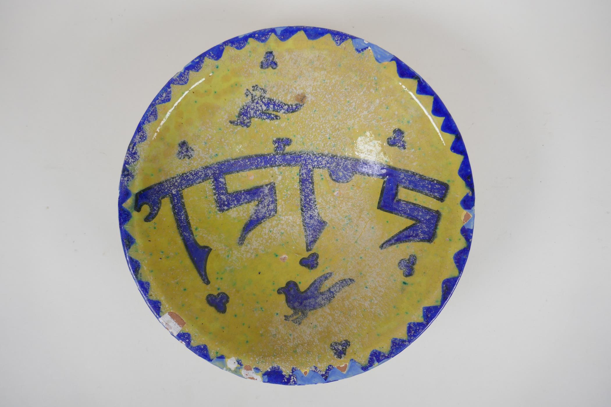 An antique Islamic pottery bowl decorated with birds and script, chips to glaze, 24cm diameter
