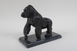 A cast bronzed metal gorilla, mounted on a marble base, 18cm high