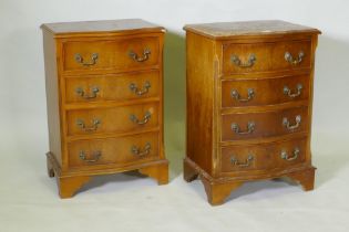 A pair of serpentine front yew wood veneered bedside chests of four drawers with brass handles,
