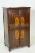 A C19th Continental mahogany four door cabinet with shell inlaid panels raised on block supports, 54