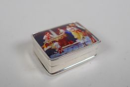 A sterling silver pill box decorated with a cold enamel plaque depicting figures in a courtyard, 3 x