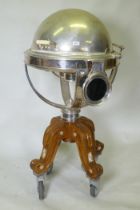 A silver plated revolving meat carving trolley with roll top cover raised on a wood base with