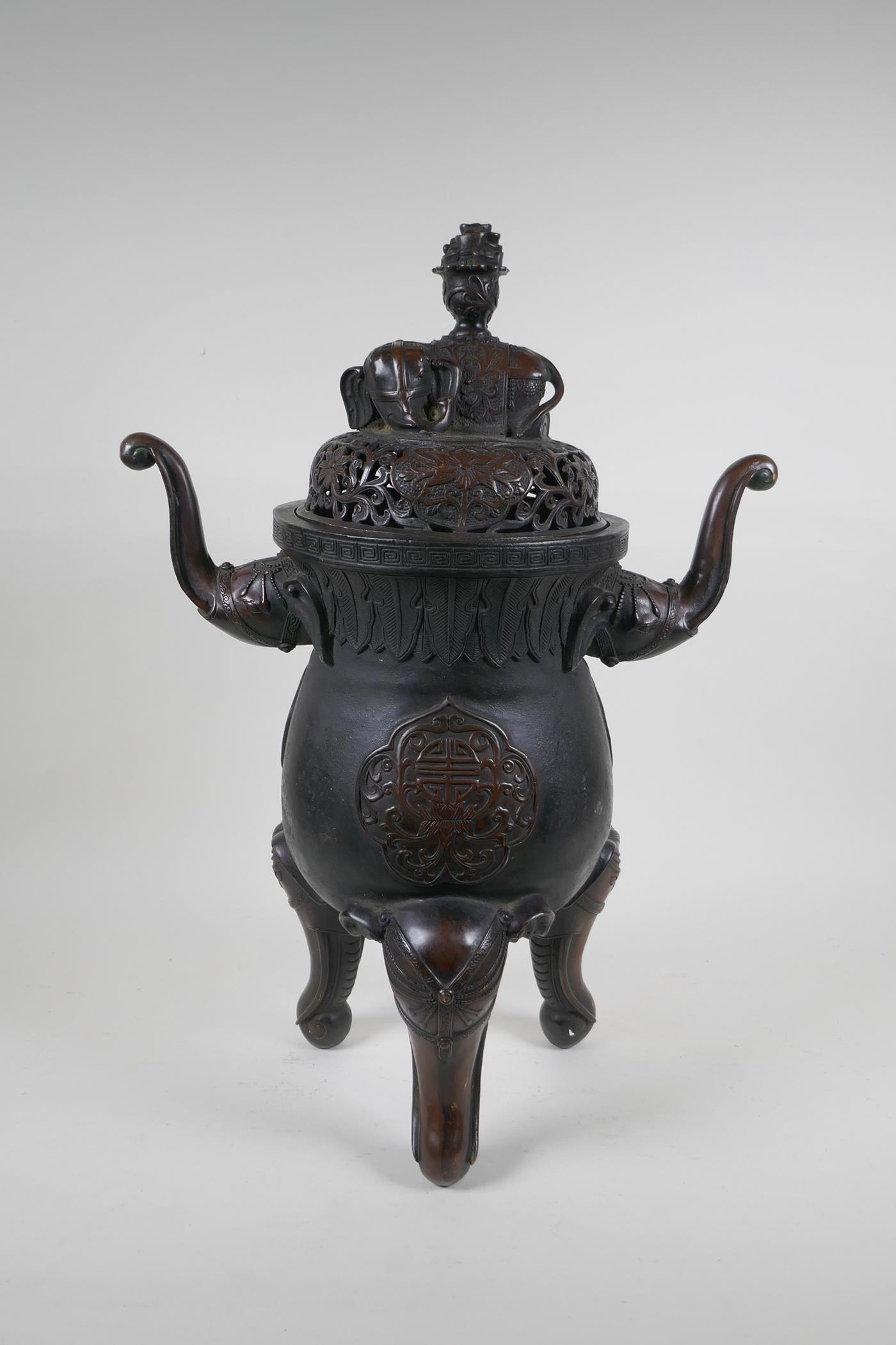 A Chinese bronzed metal two handled censer and pierced cover, raised on elephant head tripod