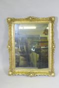 A gilt composition wall mirror with swept frame, 63 x 79cm
