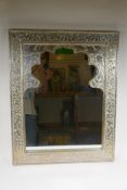 A Moorish white metal mirror with repousse floral decoration, 61 x 77cm