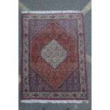 A red ground Persian Tabriz rug with multicolour allover design and cream borders, 118 x 162cm