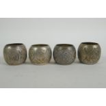 Four Iranian white metal napkin rings with chased floral pattern decoration, 4.5cm diameter